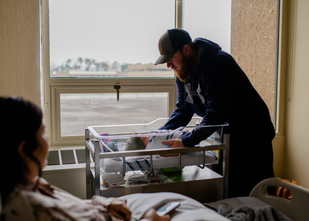 Dad places in newborn son in the bassinet in the hospital during fresh 48 